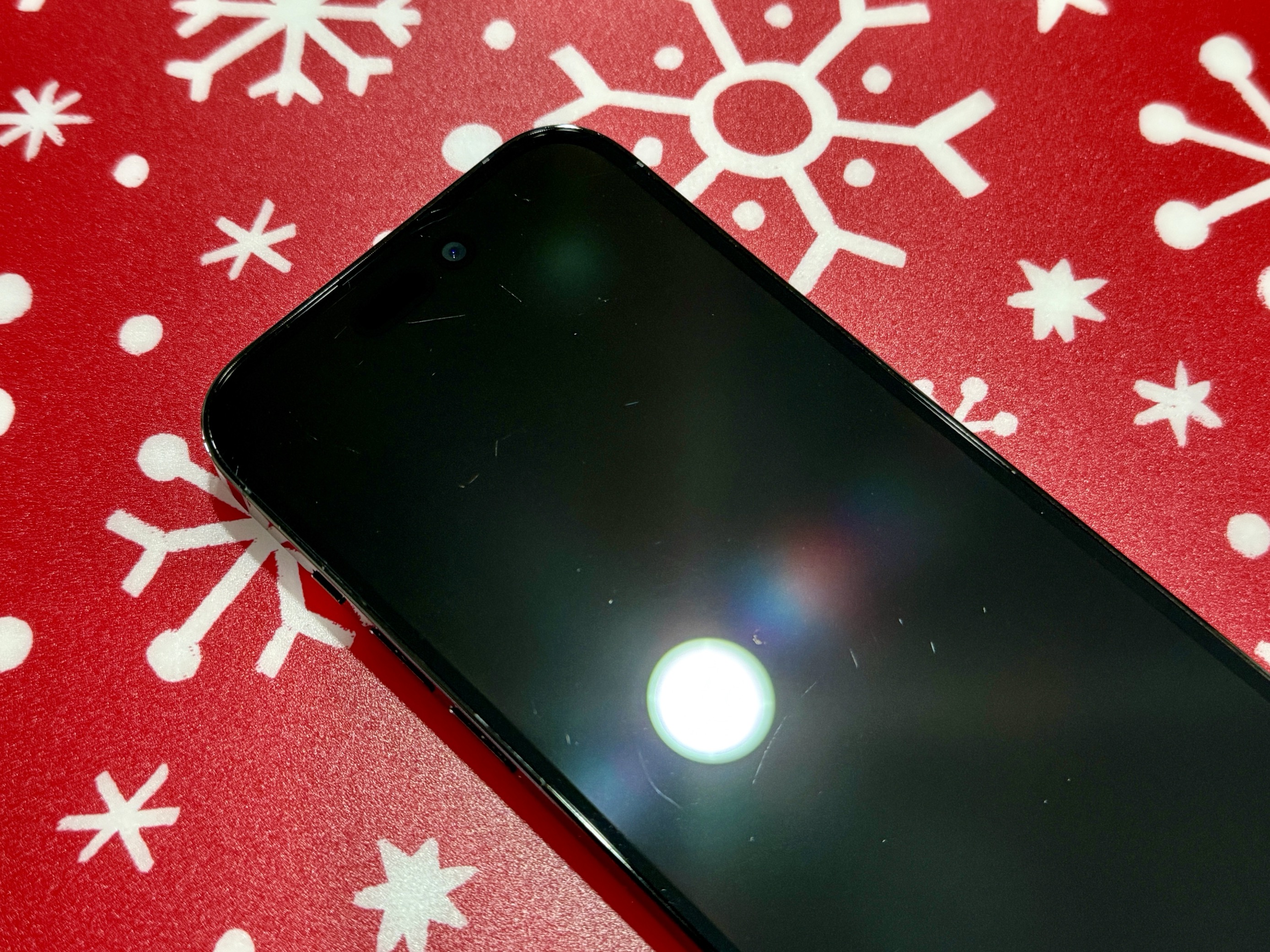 A picture of an iPhone 14 Pro, showing various scratches on its screen.