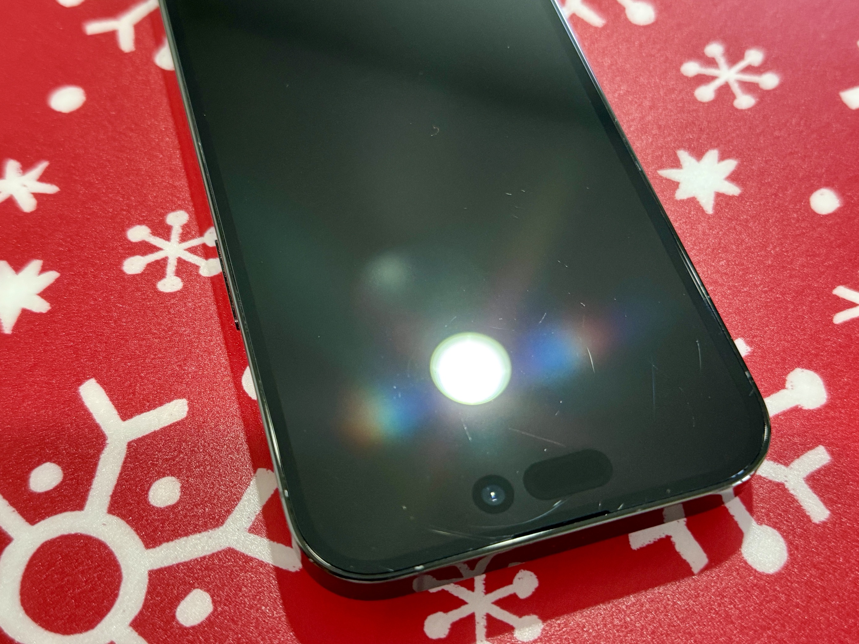 A picture of an iPhone 14 Pro, showing various scratches on its screen.