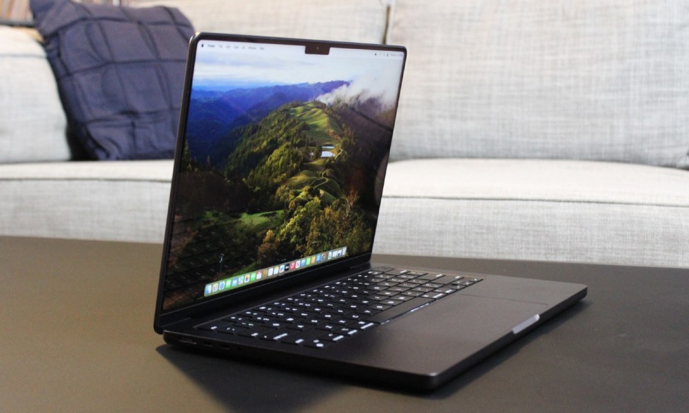 The MacBook Pro open on a table in front of a couch.