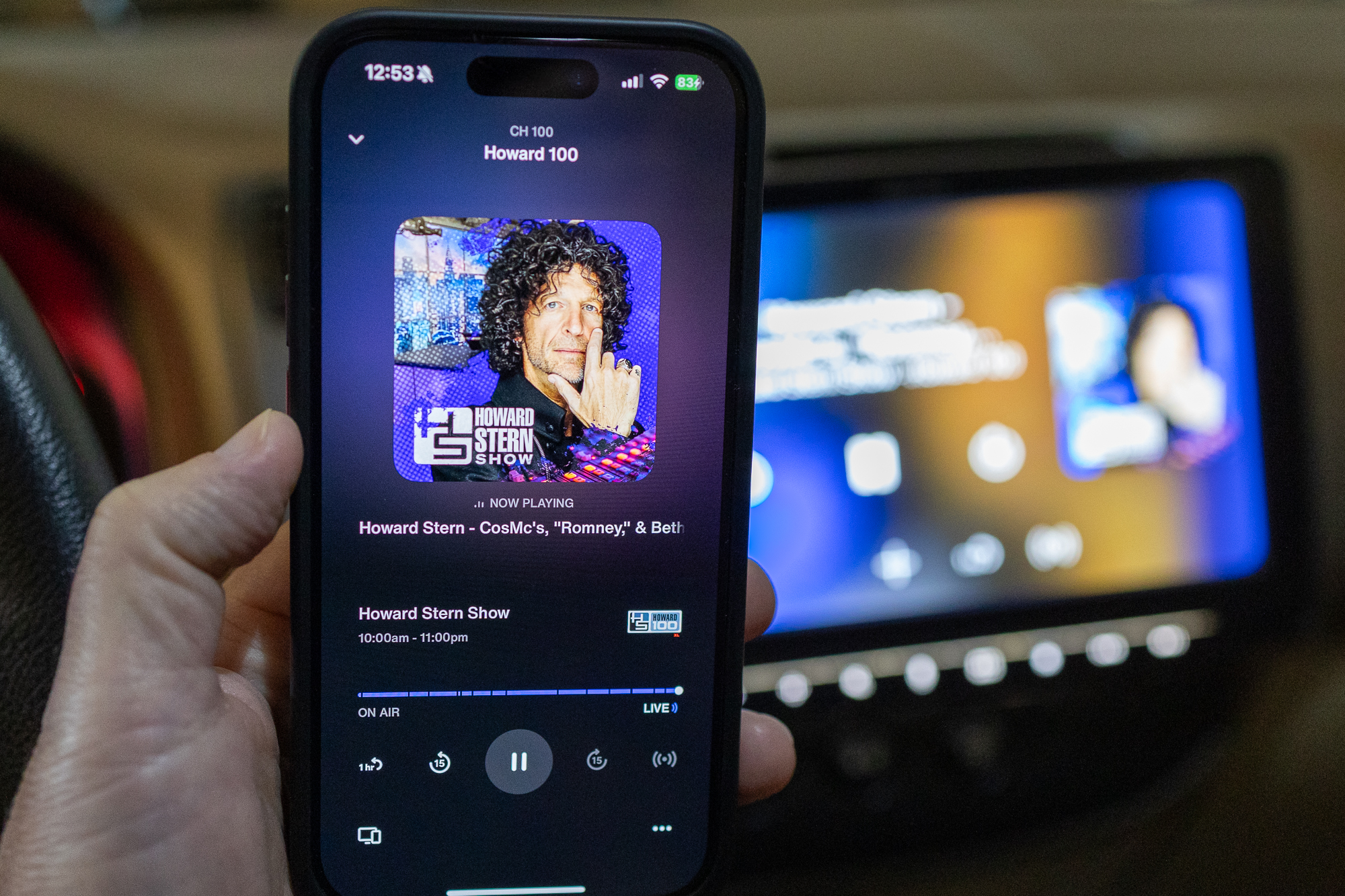 Howard Stern as seen on the new SiriusXM app on an iPhone, in front of the app on a car stereo.