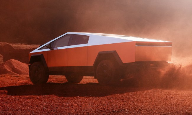 A Tesla Cybertruck throws red dust in a press photo.