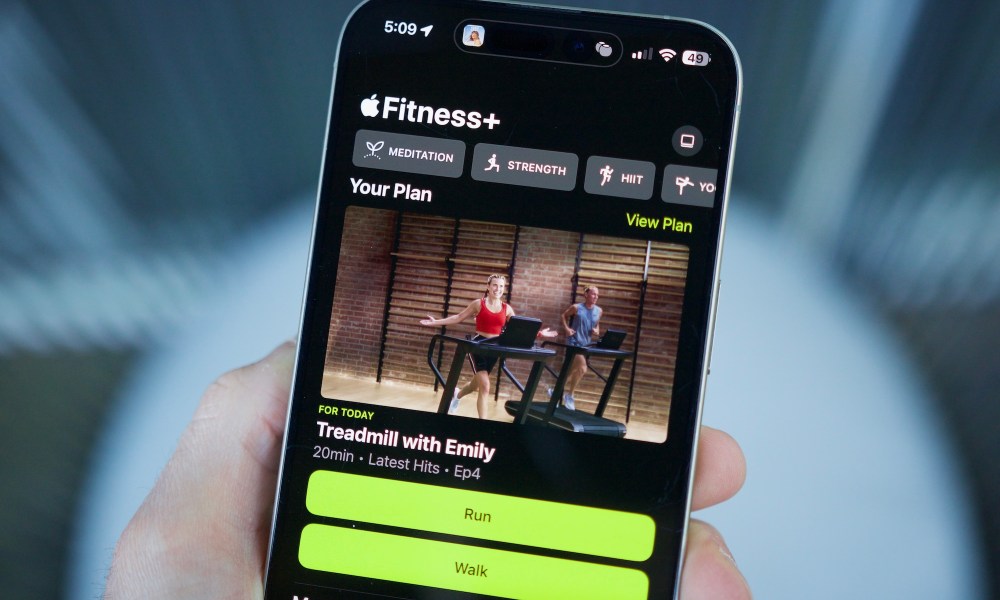 Someone holding an iPhone with the Apple Fitness app open, showing the Custom Plans feature.