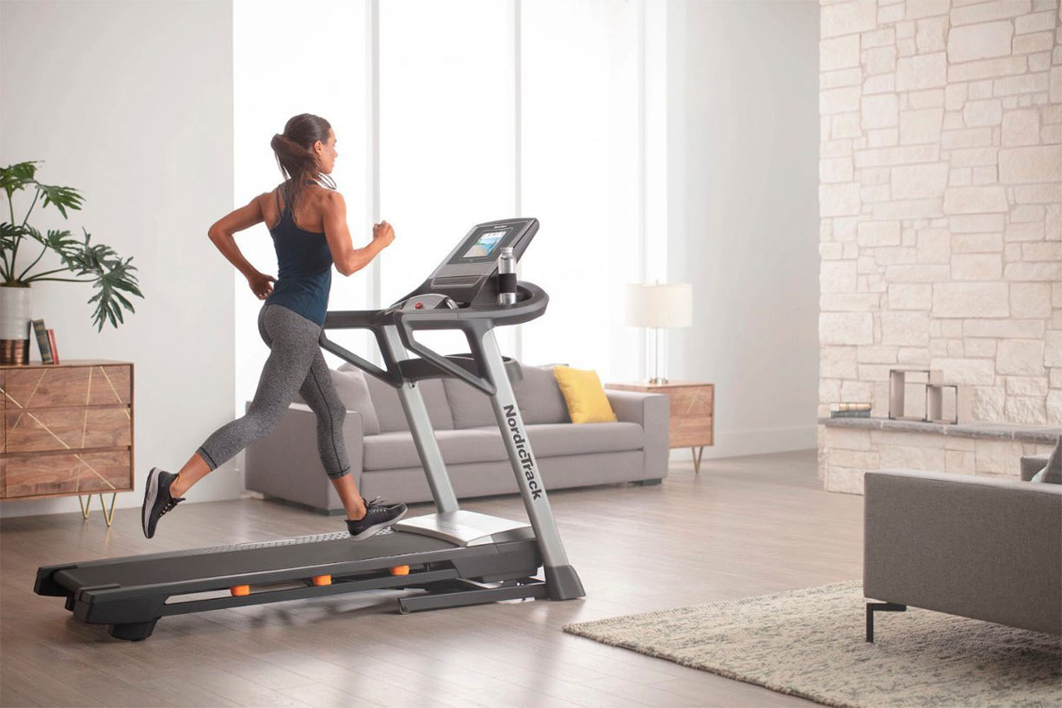 A woman using the NordicTrack T Series 8.5 S Treadmill in her living room.