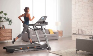 A woman using the NordicTrack T Series 8.5 S Treadmill in her living room.