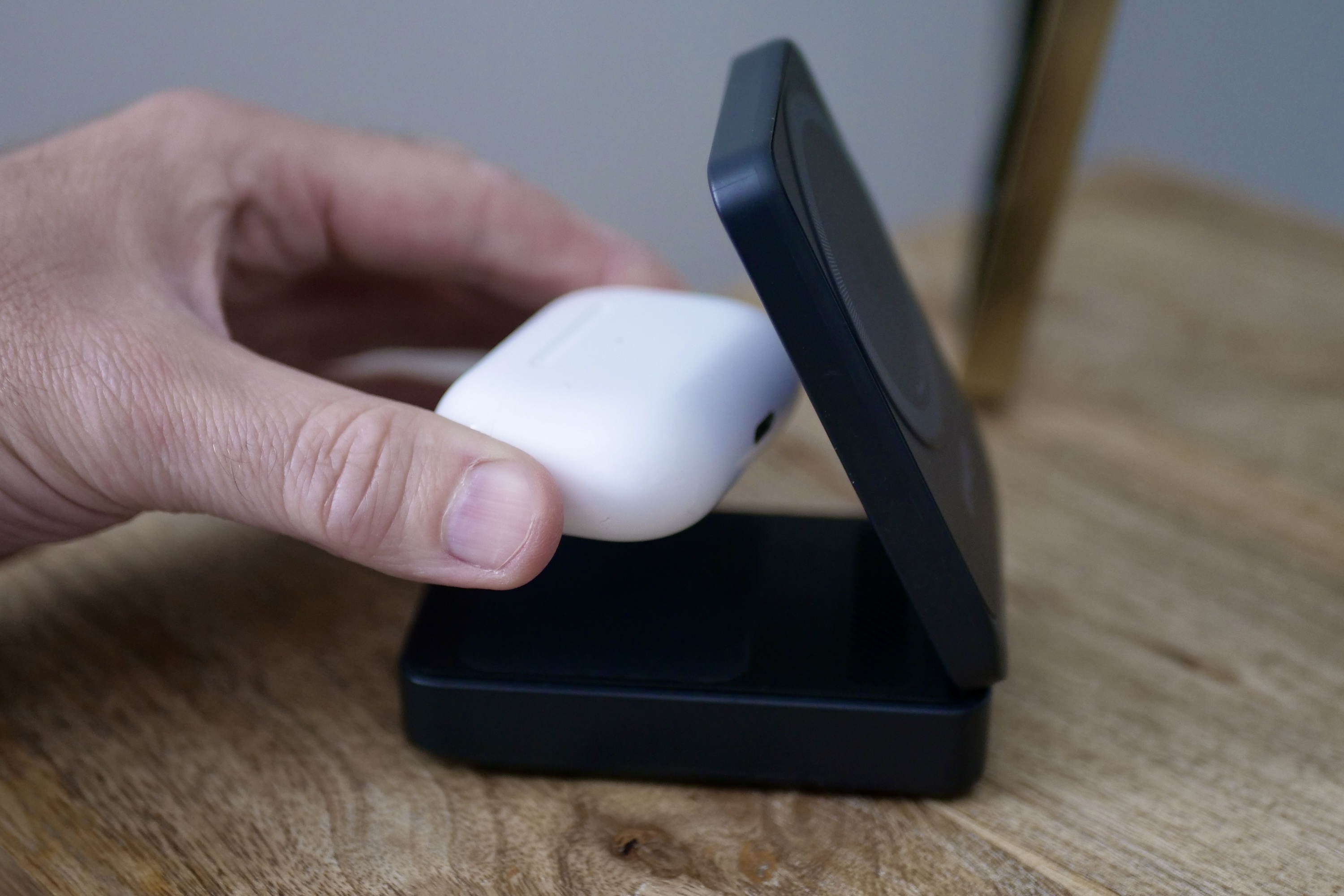 A person putting Apple AirPods on charge using the Anker MagGo Wireless Charging Station.