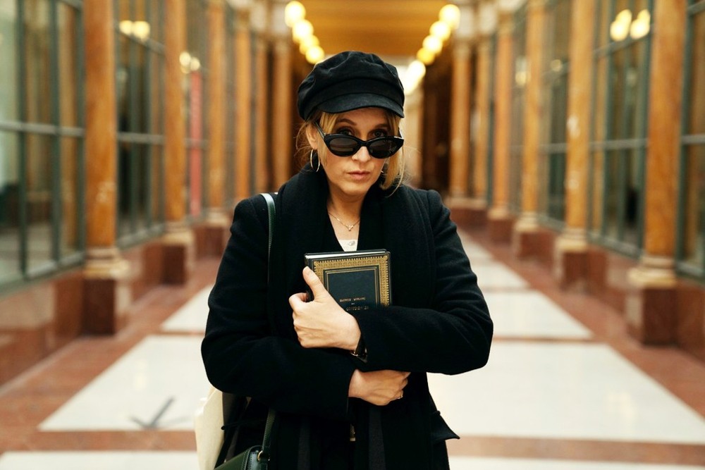 A stylish woman holds a book in Lupin.
