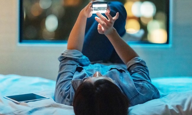 Person holding a phone while laying on a bed.