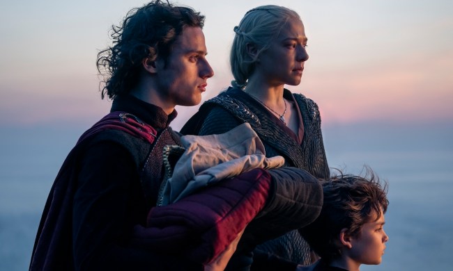 A woman stands with her two sons staring out to sea.