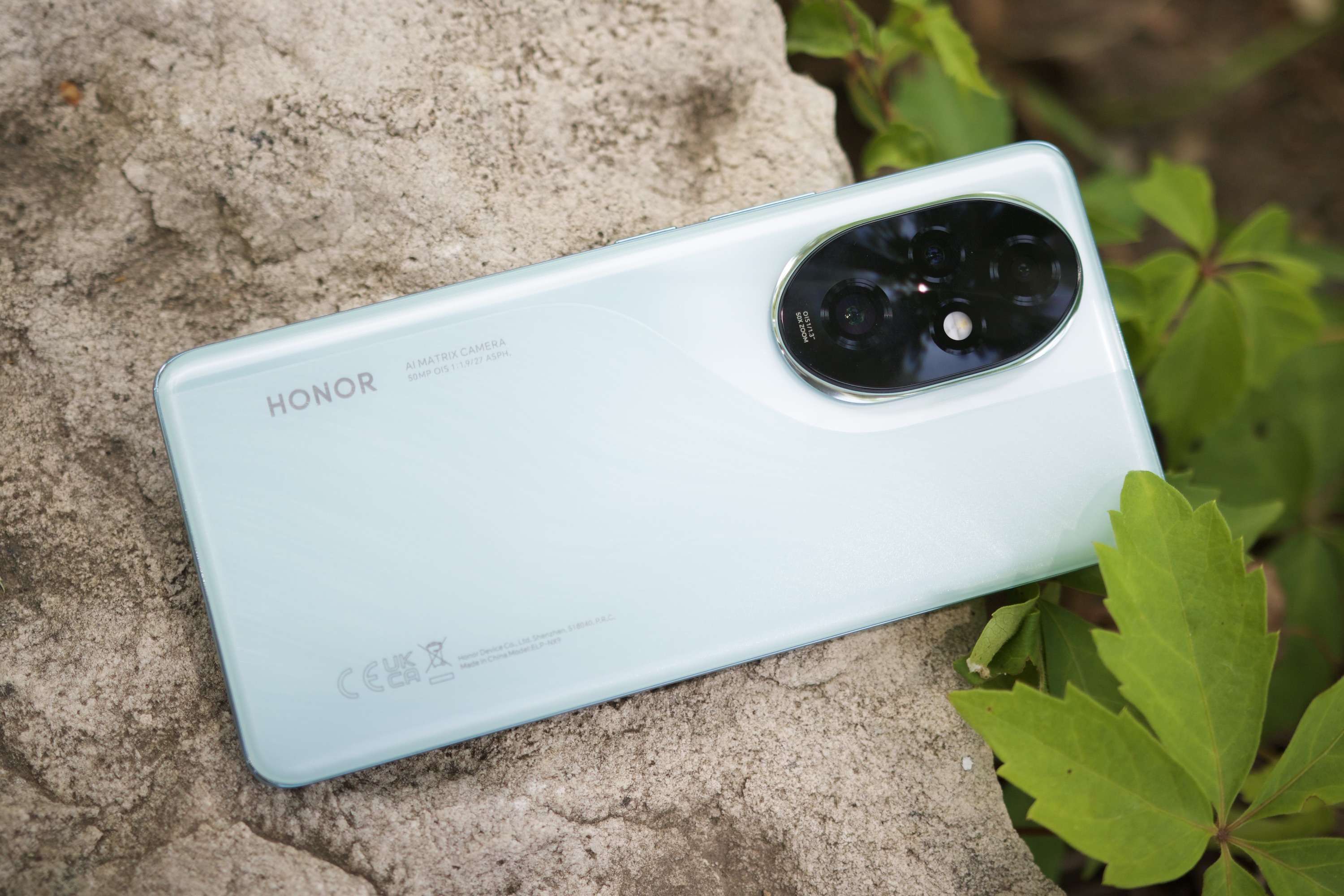 The Honor 200 Pro smartphone lying on a rock outside.