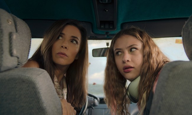 Eva Longoria in the driver's sea, a young teen beside her, both looking back in a scene from Land of Women on Apple TV+.