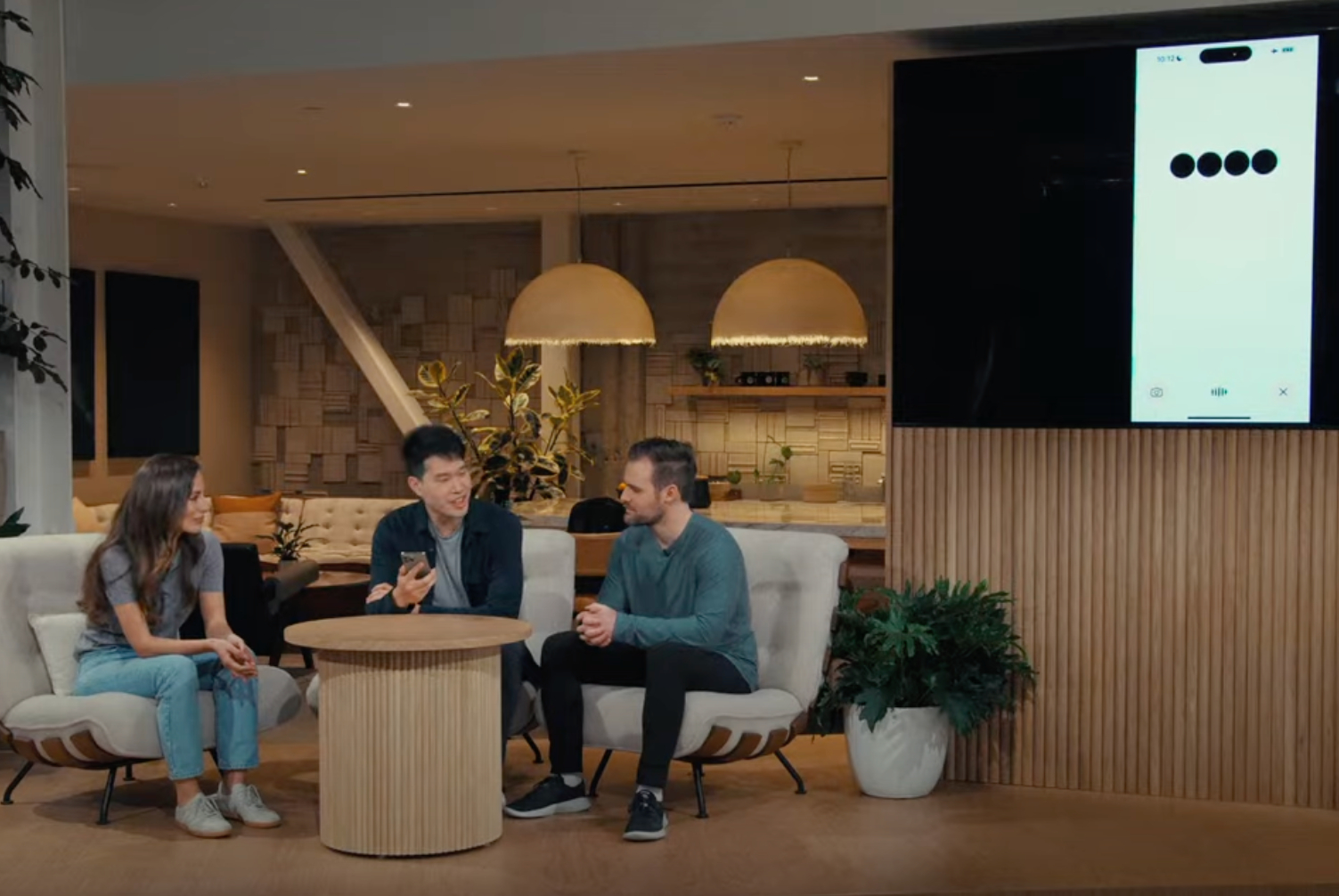 A screenshot from the OpenAI Spring Update showing three representatives on stage against a screen.