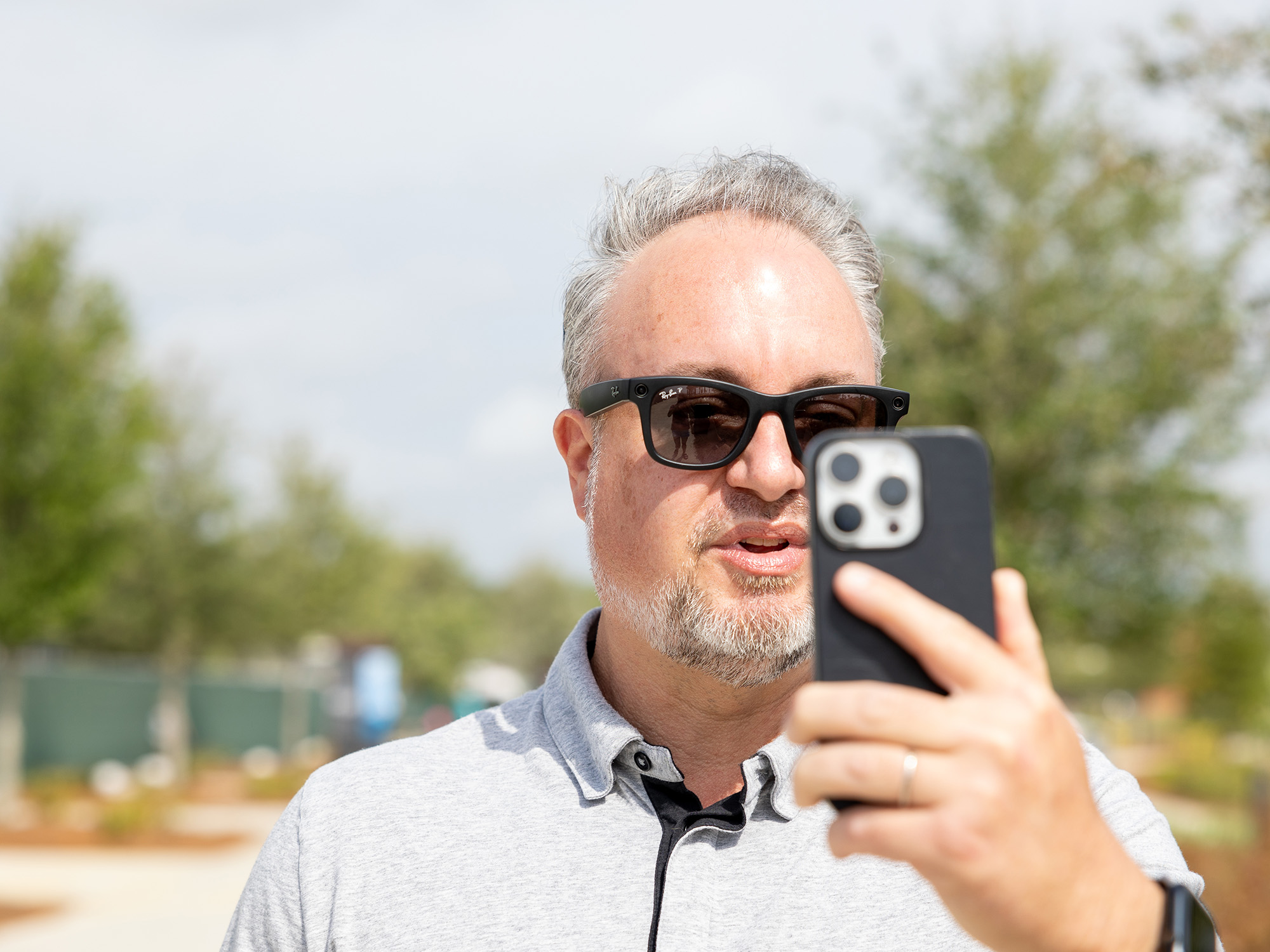 Phil Nickinson wearing the Ray-Ban Meta smart glasses while talking into an iPhone.