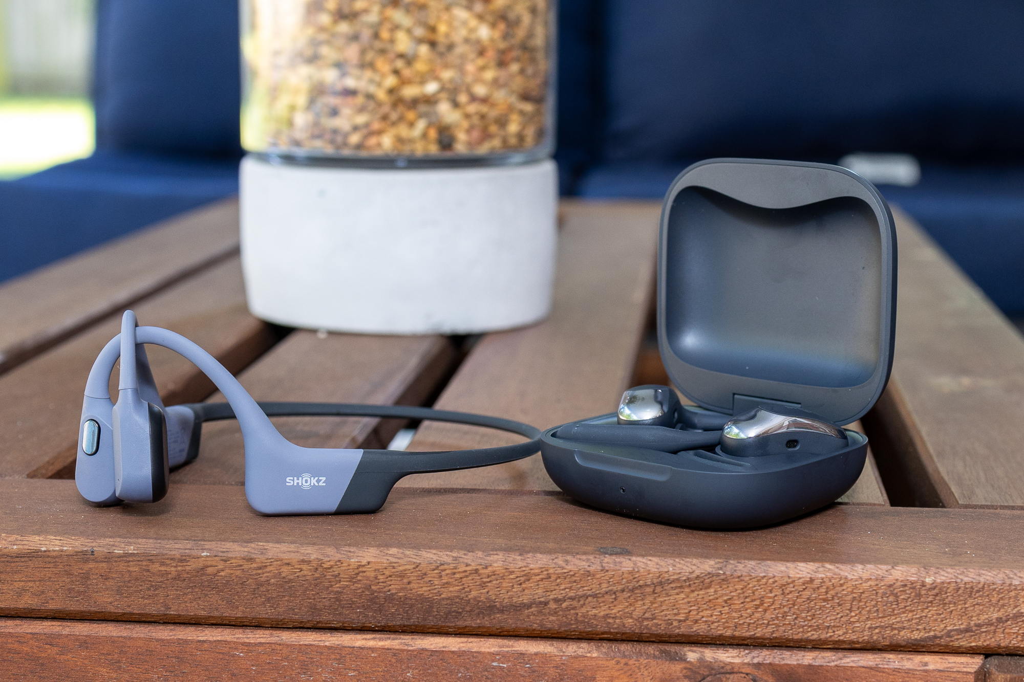 The Shokz OpenSwim Pro (left) and OpenFit Air, on a small outdoor table.
