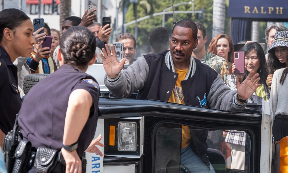 Eddie Murphy holds his hands up in front of a police officer in Beverly Hills Cop: Axel F.