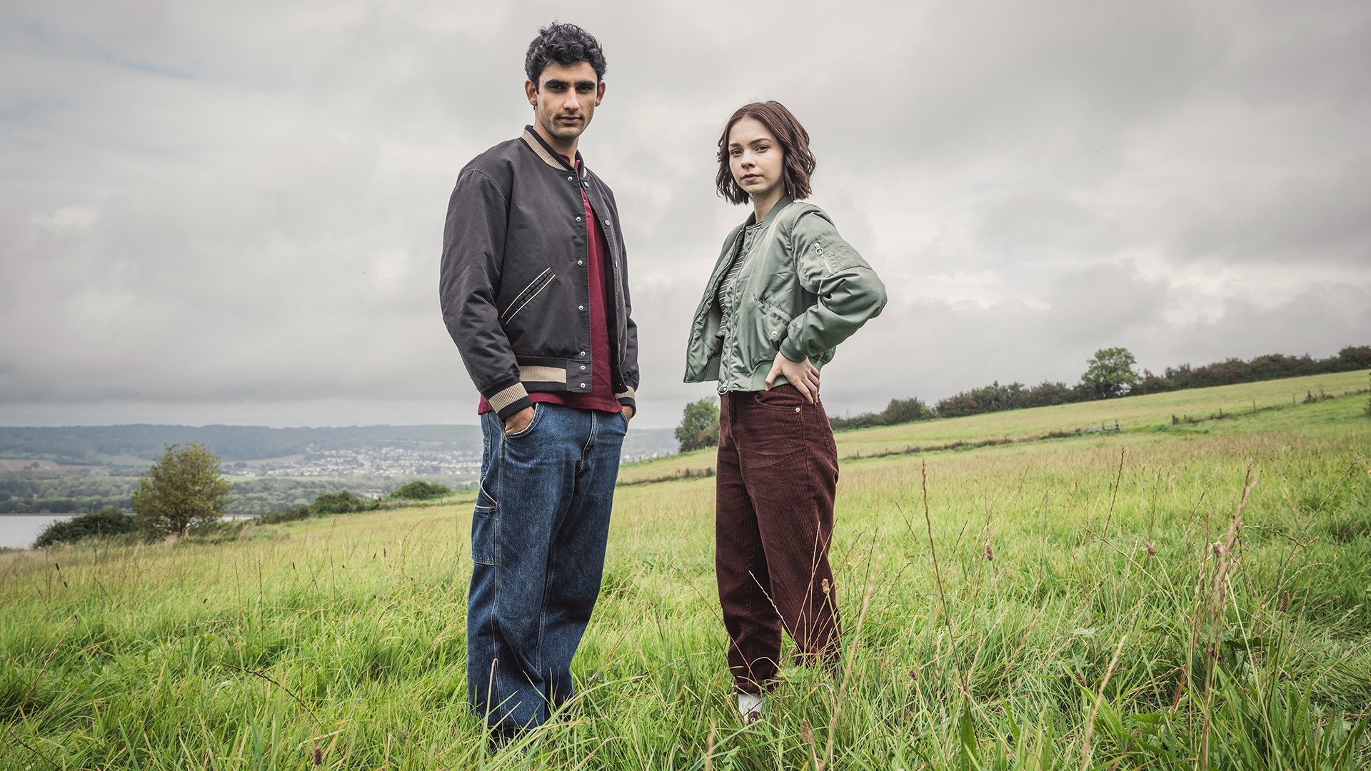 Two people stand in a field in A Good Girl's Guide to Murder.