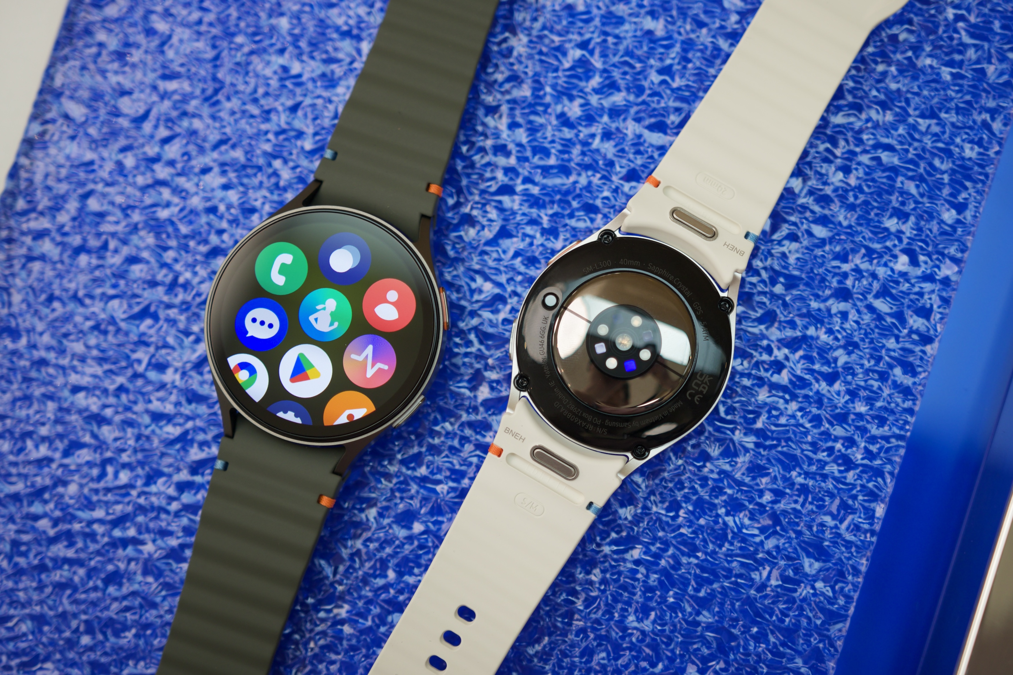 Two Samsung Galaxy Watch 7 smartwatches laying next to each other on a table.