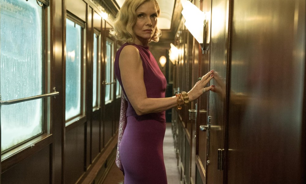 Michelle Pfeiffer puts her hands up against a wall and leans in Murder on the Orient Express.