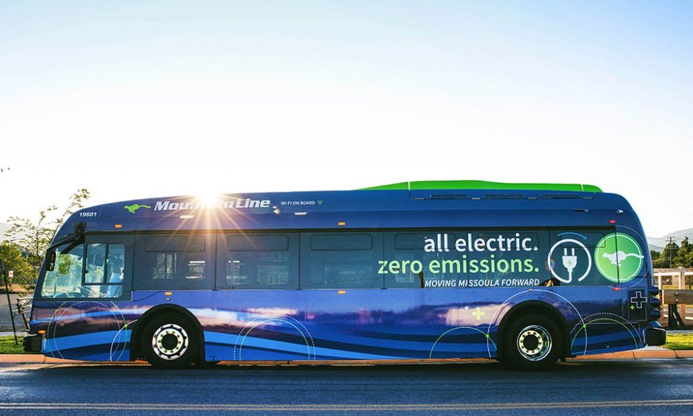 An electric bus with the sun behind it.