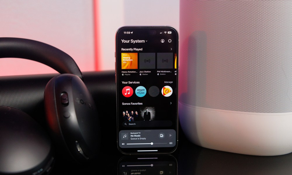 The Sonos app on an iPhone in front of Sonos speakers and headphones.