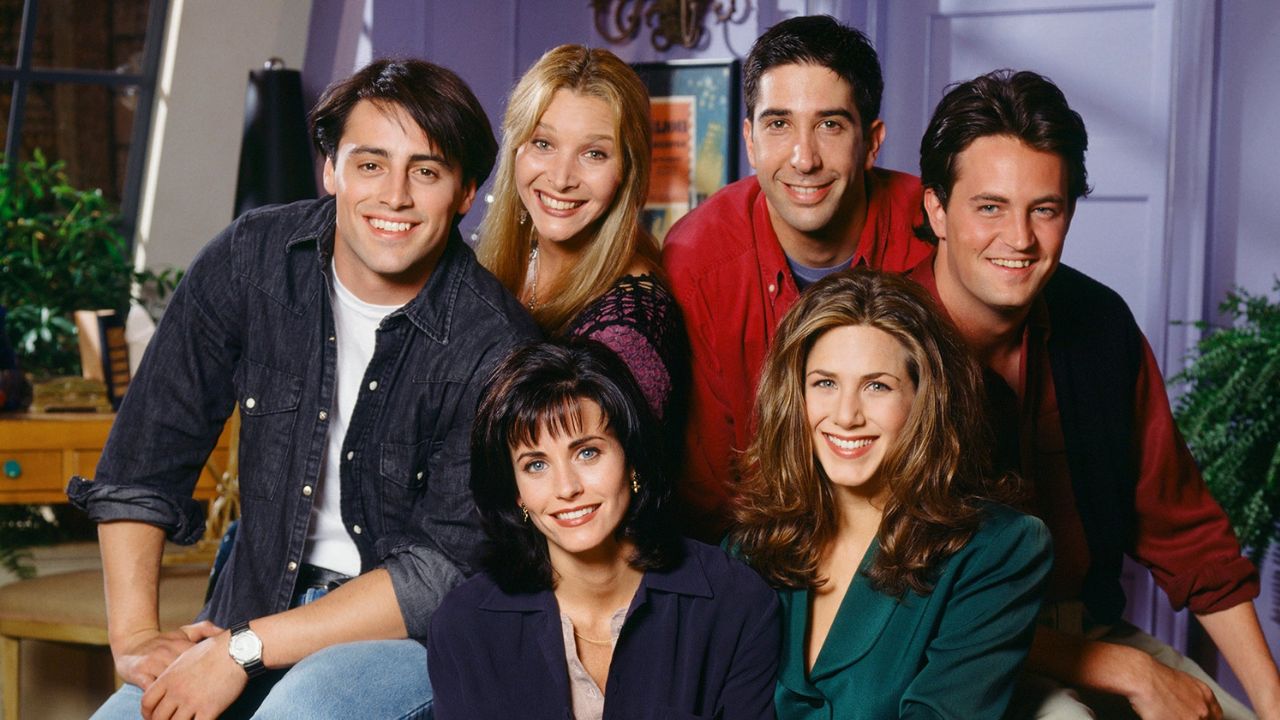 The cast of Friends season 1 smiling to the camera.