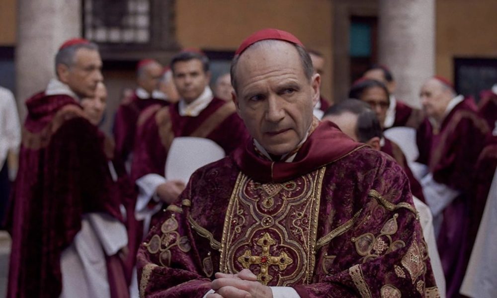 Ralph Fiennes dressed as a cardinal looks to his left.