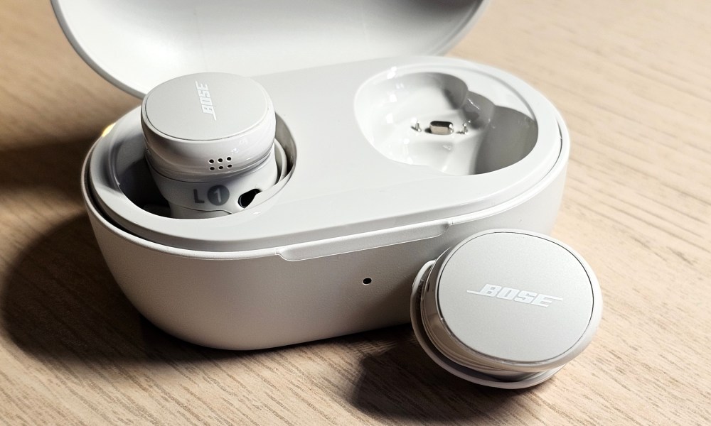 Bose QuietComfort Earbuds (2024): charging case (open, one earbud out of the case).