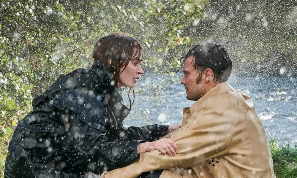 A man and a woman squat in the rain in Wild Mountain Thyme.