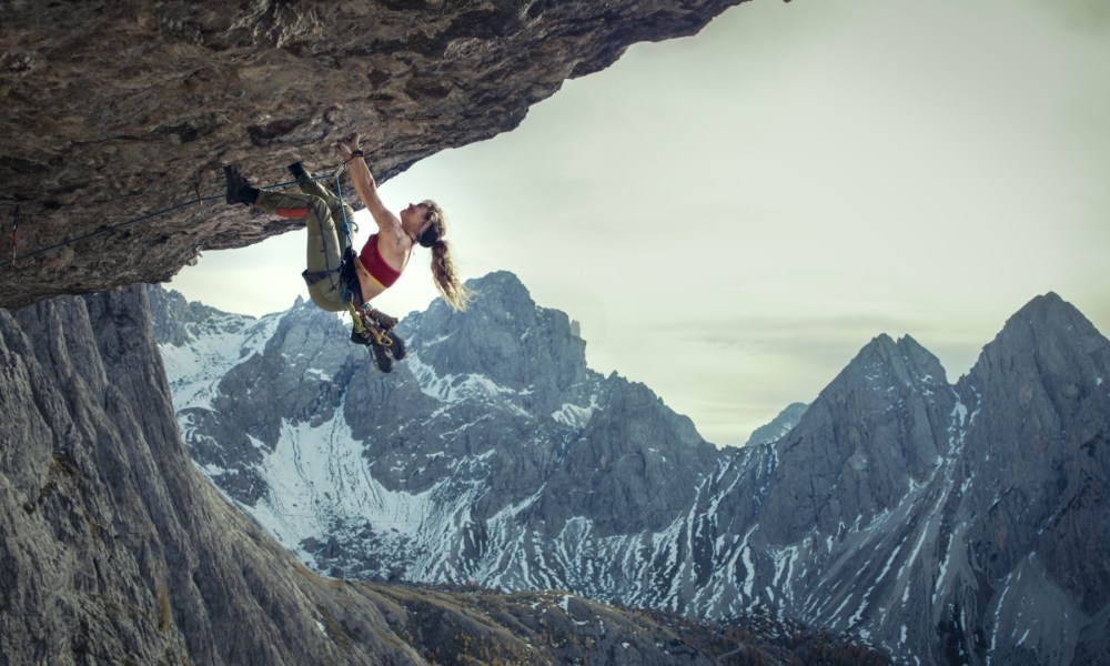 A woman hangs off a cliff as she climbs.