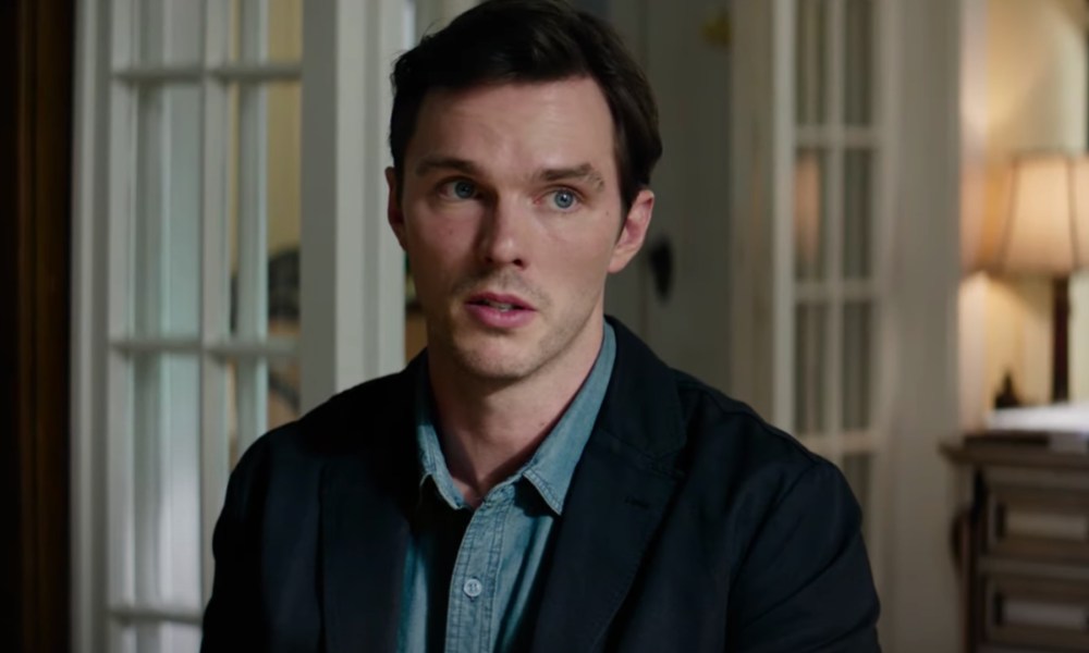 Nicholas Hoult sits down and looks worried.