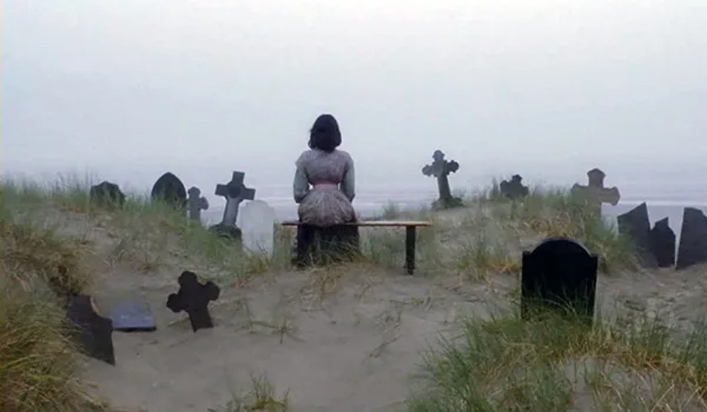 A woman sits in a graveyard in Nosferatu the Vampyre.