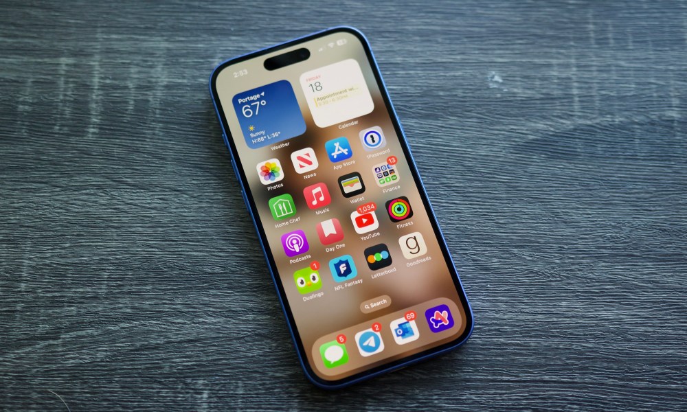 An iPhone 16 laying on a shelf with its screen on.