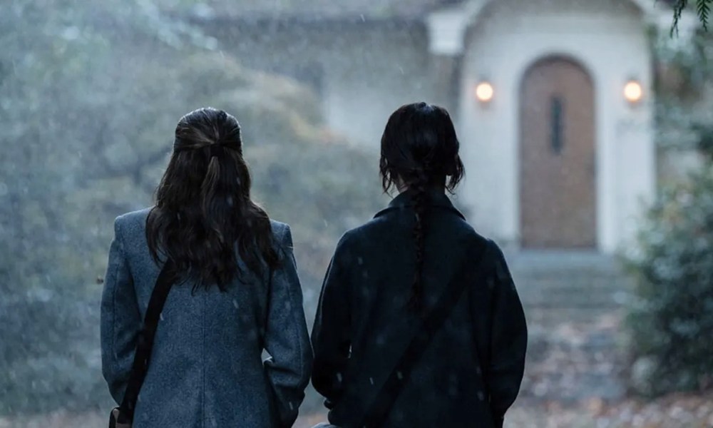 Two girls stand in front of a house in Heretic.