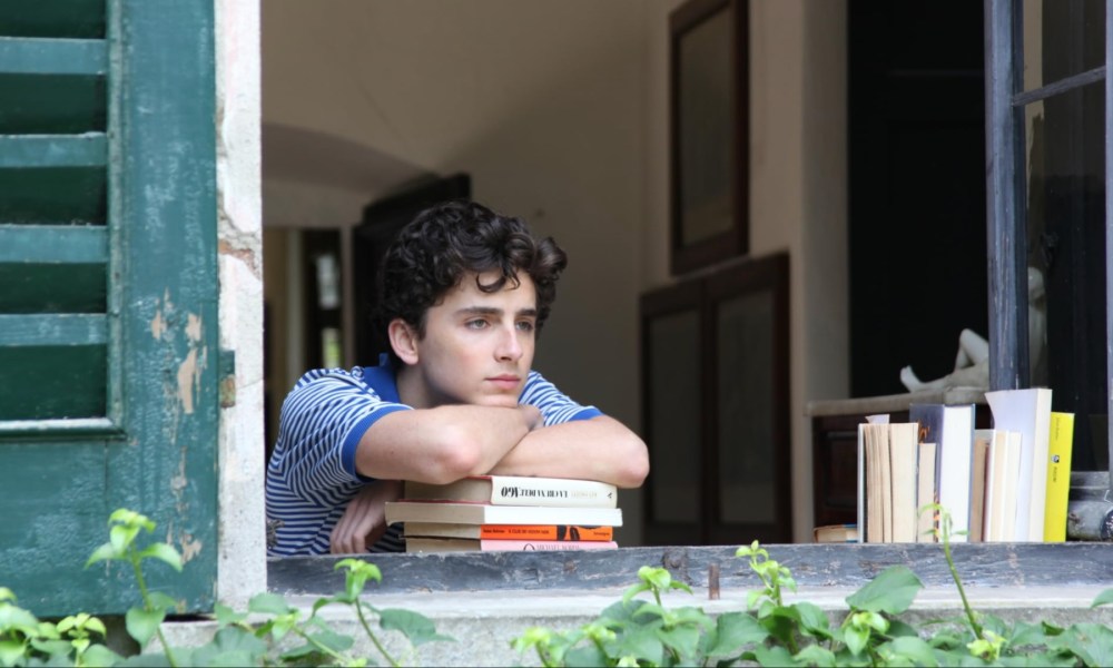 A boy puts his hands over books and leans on them.