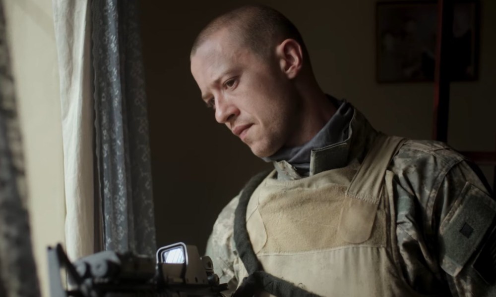 Joseph Quinn uses a gun to look through a windown in Warfare.