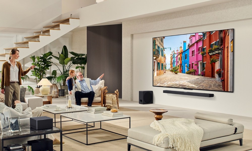 A family in thier living room, watching an LG QNED TV hanging on the wall.