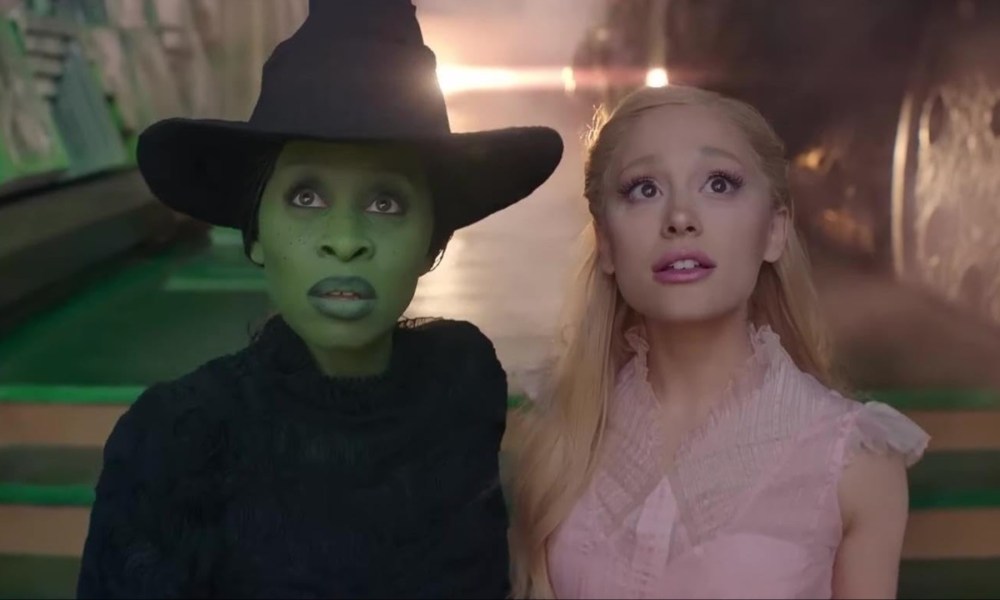 Cynthia Erivo and Arianda Grande stand next to each other and stare in a still from the movie Wicked.