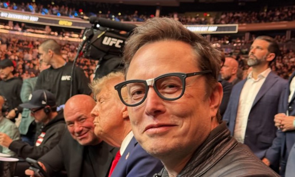 Elon Musk wearing glasses and staring at the camera.